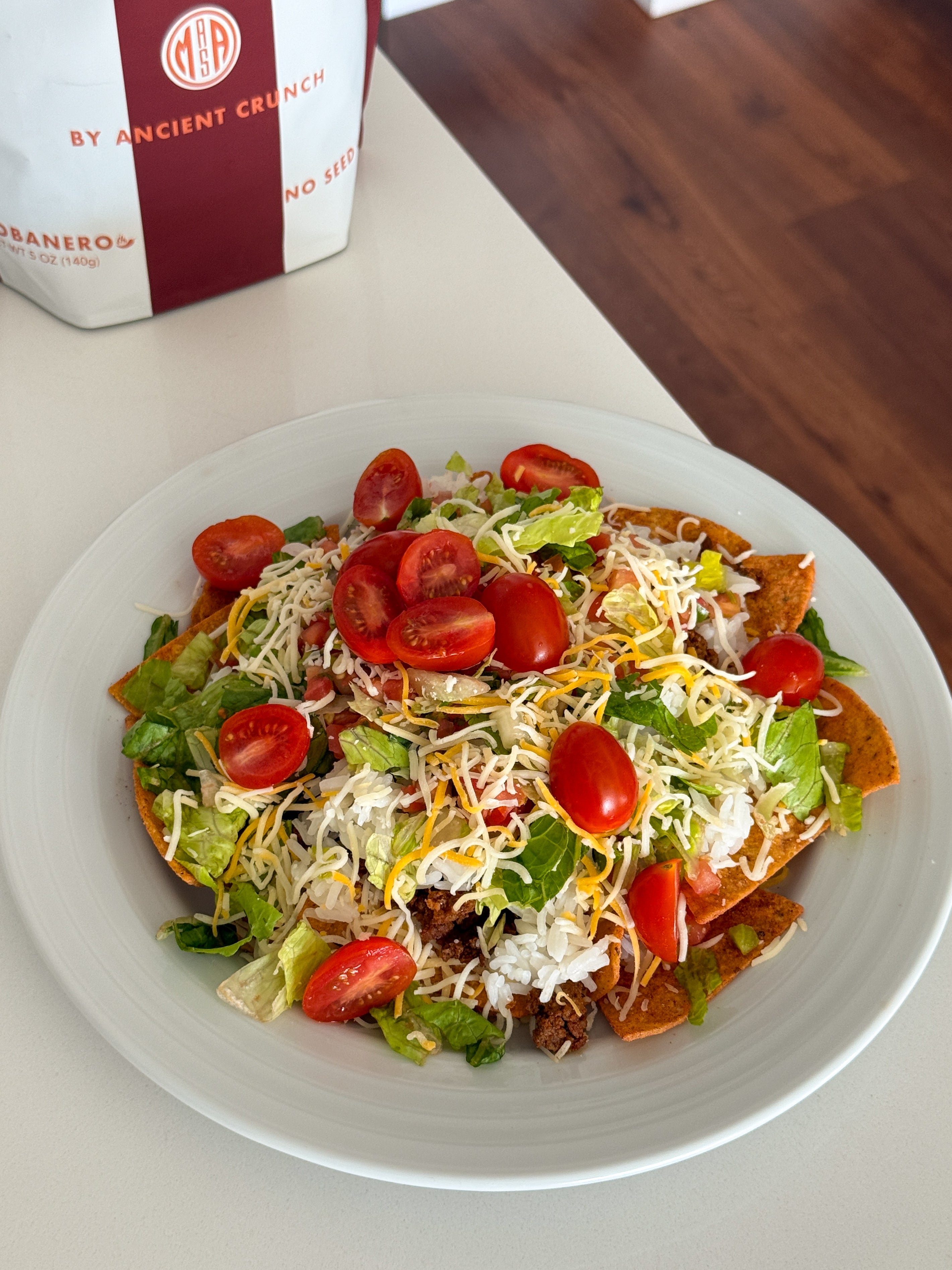 A loaded fiesta platter featuring crunchy beef tallow MASA Chips topped with seasoned ground beef, warm rice, melted cheese, and fresh garden toppings.