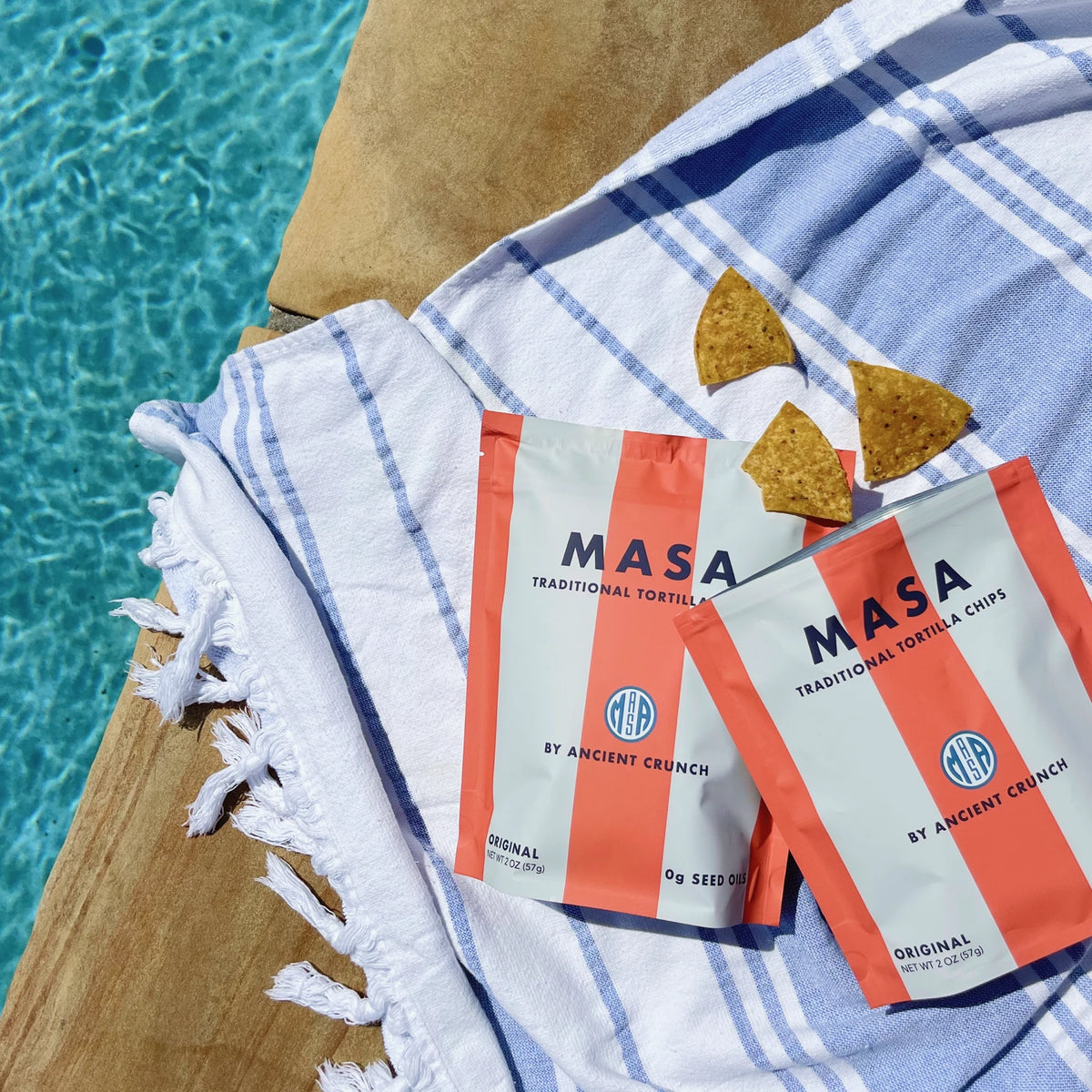 Two bags of MASA Original on a striped towel beside a pool
